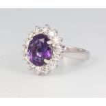 An 18ct white gold oval amethyst and diamond cluster ring, the centre stone approx. 2.11ct,