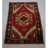An Afghan red and green ground rug with central medallion within multi row border 216cm x 140cm