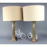 A pair of gilt metal reeded column table lamps with Doric capitals on square bases, complete with