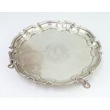 A George II silver card tray with Chippendale rim with engraved armorial, raised on hoof feet,