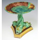 A 19th Century English Majolica tazza decorated with leaves, the base with 3 dolphins on a triform