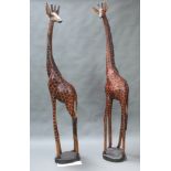 A large and impressive pair of African carved hardwood figures of giraffes raised on circular
