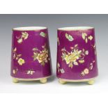 A pair of Edwardian circular tapered purple ground vases decorated with flowers raised on ball