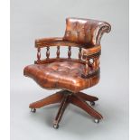 A captain's style revolving office chair with spindle decoration, upholstered in green leather
