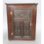 A Victorian carved oak corner cabinet with moulded cornice, fitted shelves enclosed by carved