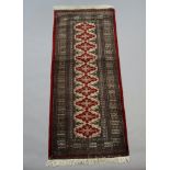 A red and brown ground Bokhara runner with 10 stylised diamonds to the centre within a multi row