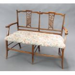 An Edwardian double chair back settee with vase shaped slat back and upholstered seat, raised on