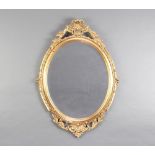 An oval bevelled plate wall mirror contained in a decorative gilt frame with swag decoration 76cm