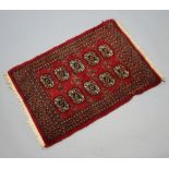 A red and black ground Bokhara rug with 10 octagons to the centre 90cm x 63cm Signs of old moth