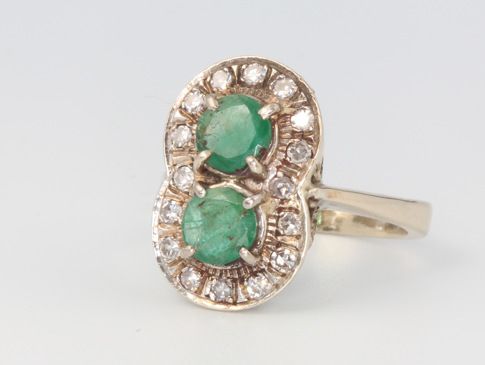 A white metal (marked 750) emerald and diamond double cluster ring, 7 grams, size O 1/2