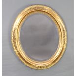 A Georgian style oval bevelled plate wall mirror contained in a decorative gilt frame with rose