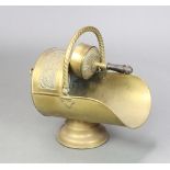 A Victorian embossed brass helmet shaped coal scuttle with swing handle and circular base,