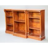 A Victorian style mahogany inverted breakfront bookcase fitted adjustable shelves, raised on a