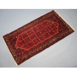 An Afghan red and blue ground rug with diamond shaped medallion to the centre 197cm x 107cm