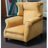 A winged armchair raised on turned supports upholstered in yellow material 85cm h x 76cm w x 78cm