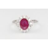 An 18ct white gold oval ruby and diamond ring, the centre stone 1.26ct surrounded by brilliant and