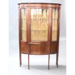 An Edwardian inlaid mahogany display cabinet of serpentine outline, the upper section enclosed by