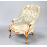 A Victorian walnut showframe armchair upholstered in green buttoned material, raised on cabriole