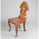 A Victorian carved mahogany hall chair with shaped back with and solid seat, raised on cabriole