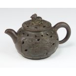 A tanware teapot with reticulated lid and body, the finial in the form of a shi shi, the body with