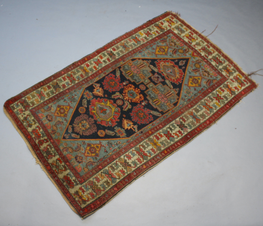 A North West Persian red and blue ground rug with shaped medallion to the centre within a multi