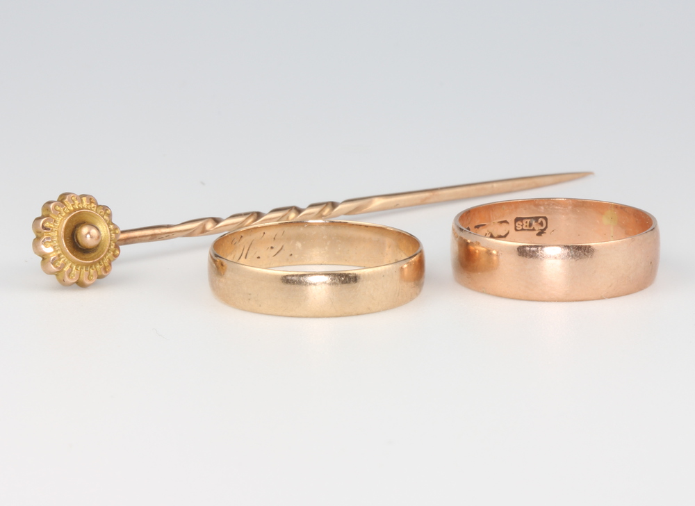 A 9ct yellow gold wedding band size O 1/2, 1.3 grams, a yellow metal ditto 2 grams and a 9ct pin 1.5