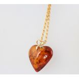 A Continental yellow metal necklace 48cm with an amberoid heart pendant, 10 grams