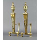 A pair of Adams style polished brass fire dogs with lidded urn decoration and swags to the front