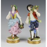 A pair of Volkstedt porcelain figures of a female and male flower seller raised on circular bases