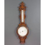 A Victorian aneroid barometer and thermometer contained in a carved oak wheel case 88cm x 26cm