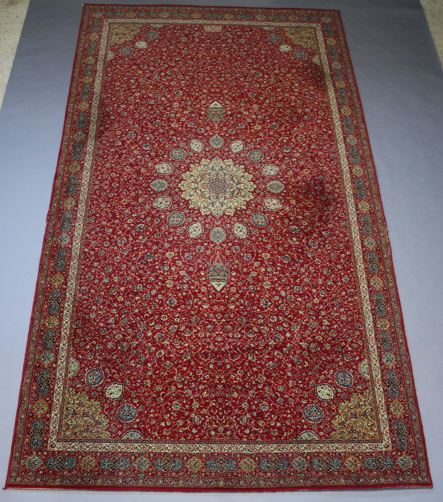 A red and green ground machine made Persian style carpet with central medallion 409cm x 229cm