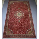 A red and green ground machine made Persian style carpet with central medallion 409cm x 229cm