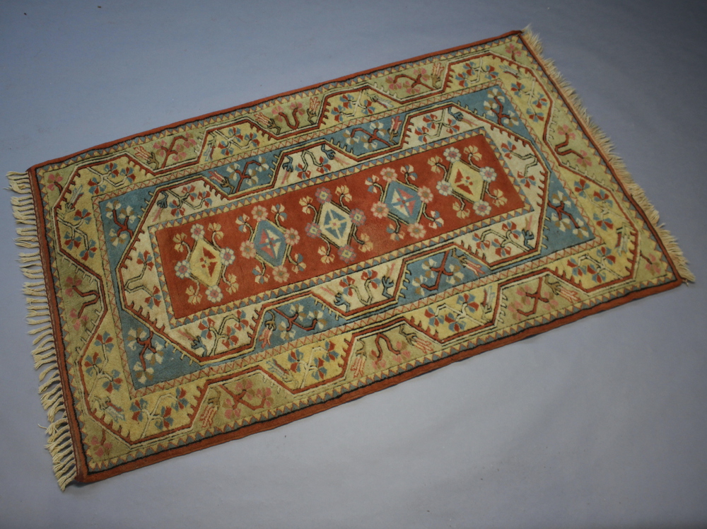 An orange, blue and white Caucasian style rug the central medallion with 5 stylised diamonds to