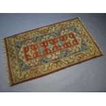 An orange, blue and white Caucasian style rug the central medallion with 5 stylised diamonds to