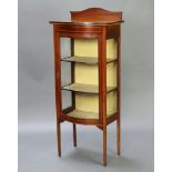 An Edwardian inlaid mahogany bow front display cabinet with arched raised back, fitted shelves