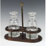 A pair of mallet shaped decanters with mushroom stoppers in a mahogany finished 2 bottle rack