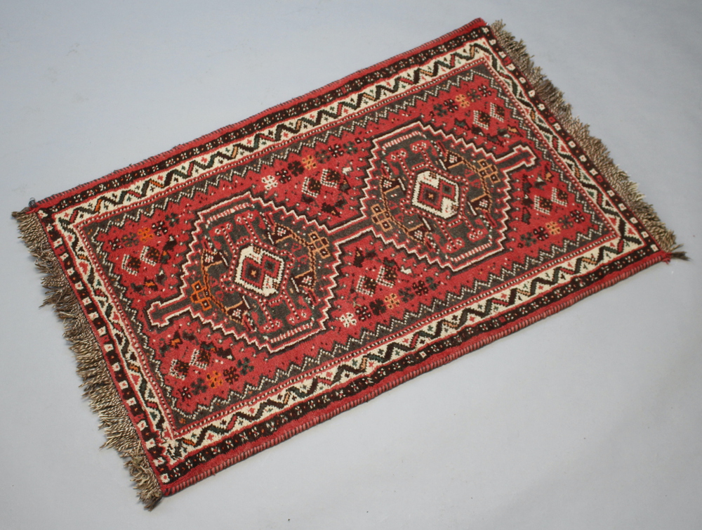 A red, white and black ground Afghan rug with 2 stylised octagons to the centre 127cm x 80cm