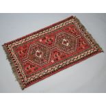 A red, white and black ground Afghan rug with 2 stylised octagons to the centre 127cm x 80cm