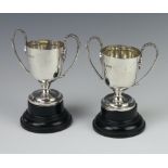 A pair of Edwardian silver 2 handled trophy cups on wooden socles 9cm, 176 grams, Chester 1910