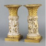 A pair of 19th/20th Century bronze cylindrical vases supported by cherubs, raised on square bases