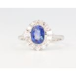 An 18ct white gold oval sapphire and diamond cluster ring, the oval cut stone approx. 1.74ct flanked
