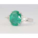 An 18ct white gold oval emerald and diamond ring, the centre cut stone approx 3.89ct, the triangular