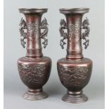 A pair of 19th Century Japanese bronze twin handled club shaped vases, raised on a circular