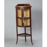 An Edwardian inlaid mahogany bow front corner cabinet with raised back, fitted shelves enclosed by