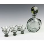 A grey smokey glass liqueur decanter with circular stopper and six tapered totsOne of the tots is