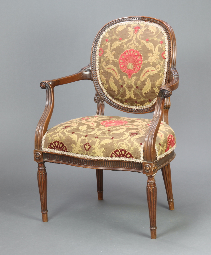 A 1930's carved mahogany open arm salon chair, the seat and back upholstered in floral material,