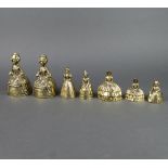 7 various brass table bells in the form of crinoline ladies 15cm h - 8cm h