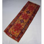 A red and tan ground Heriz runner with stylised medallions to the centre within a 3 row border 301cm