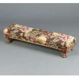 A Victorian carved walnut show frame footstool upholstered in floral material, raised on carved