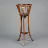 A circular Edwardian inlaid mahogany jardiniere stand raised on outswept supports with shaped